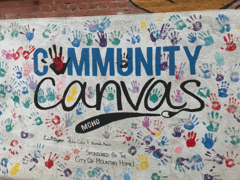 This mural is of the Community Canvas logo and has dozens of multi-colored handprints across it